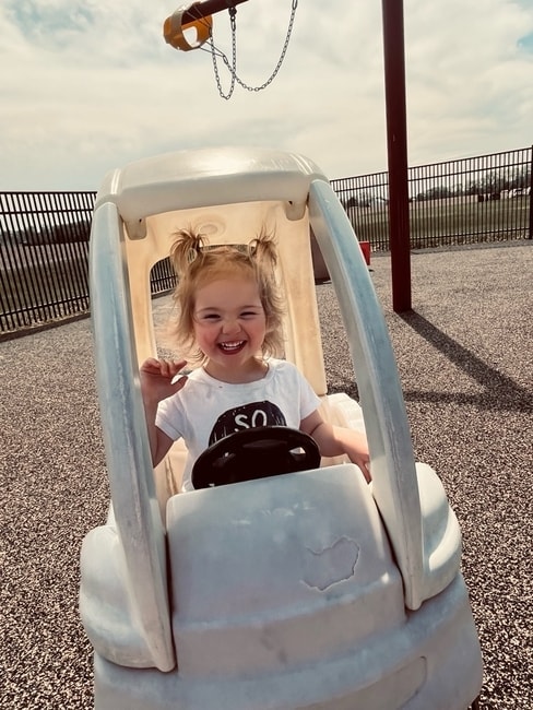 Toddler girl riding a play car outside